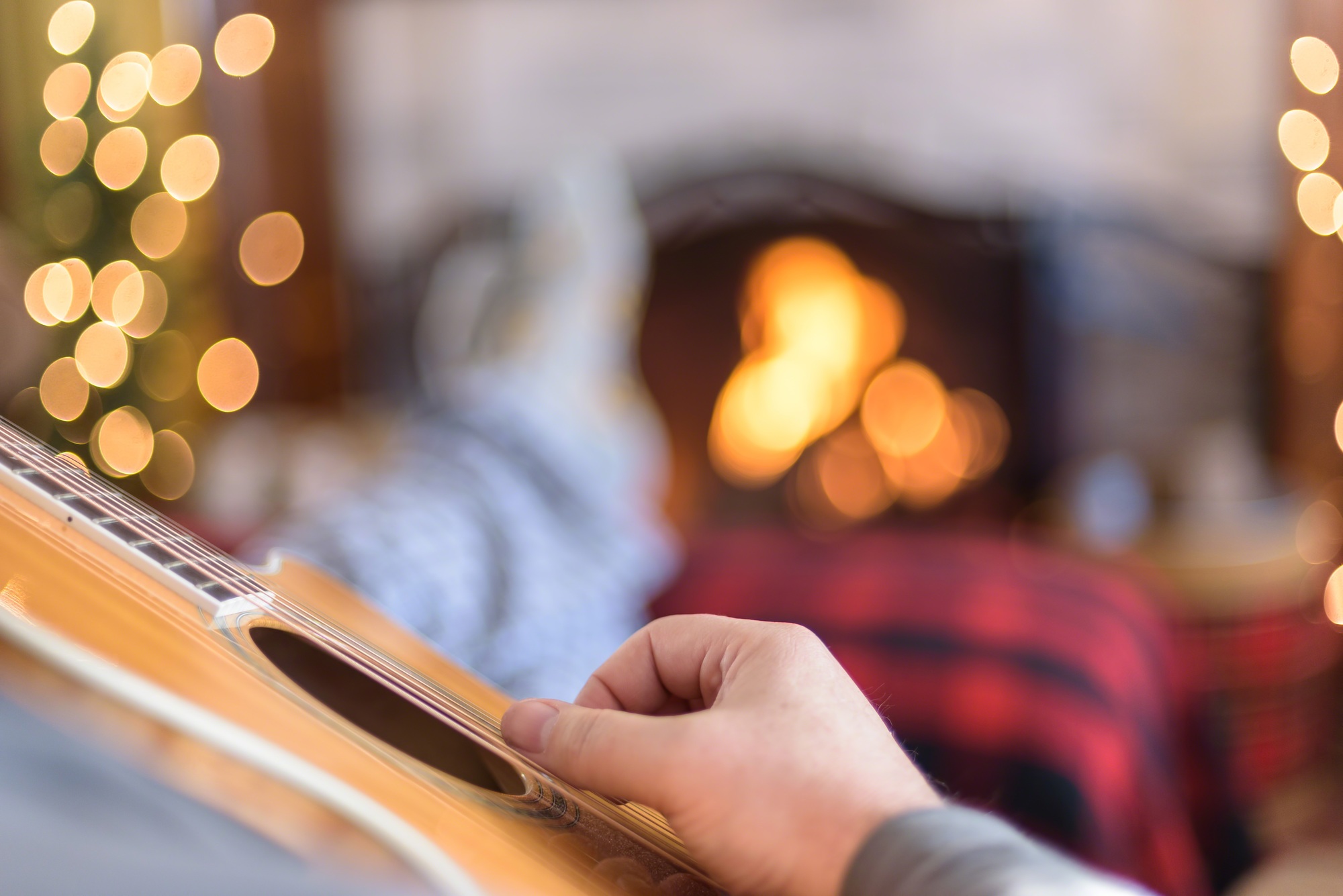 Strumming acoustic guitar by the fireplace in winter